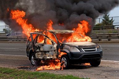 Car on fire next to a road