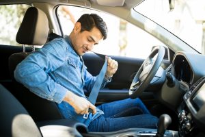 man in driver's seat buckles his seat belt